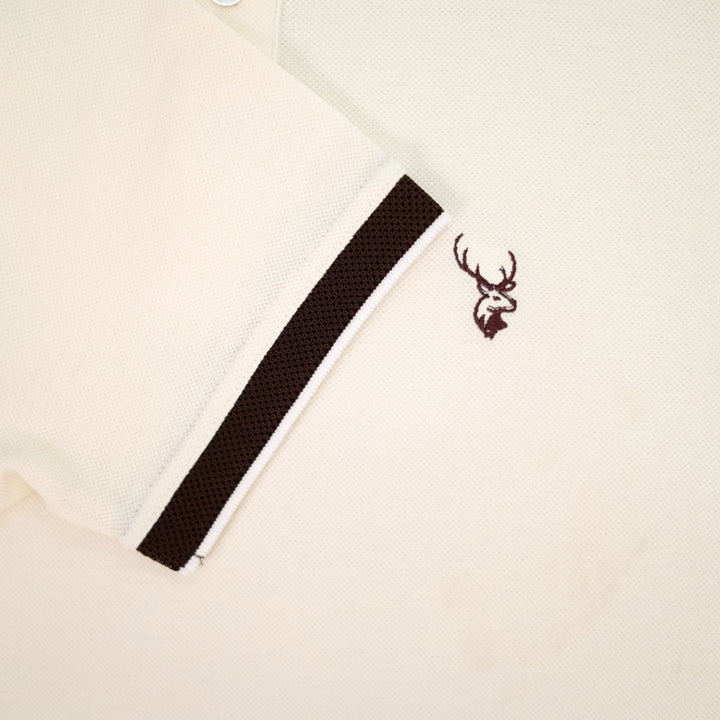 Close-up of a beige fabric with a black stripe and a fils logo emblem.