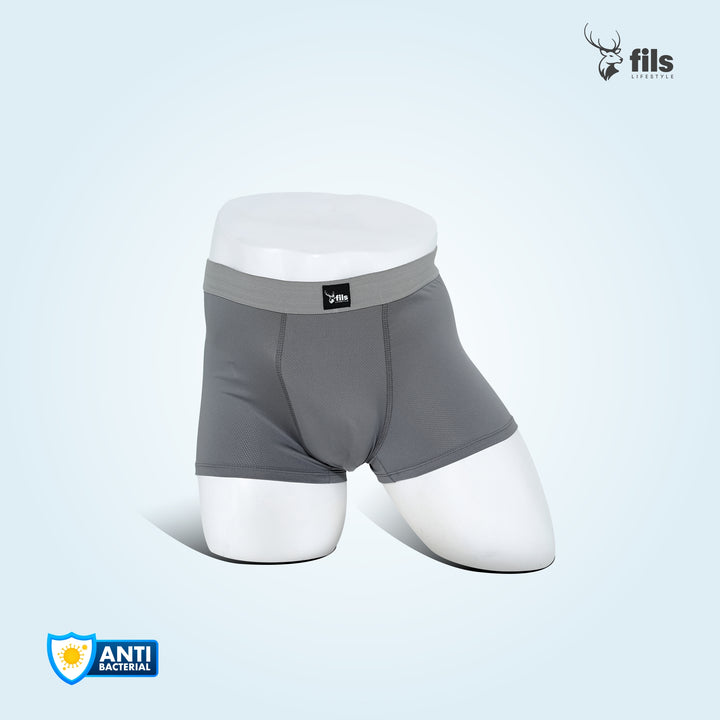 Gray boxer briefs with white waistband on a dark urban street background, featuring the brand 'fils'.