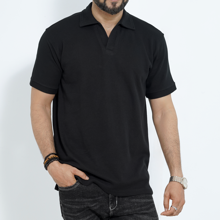 Man wearing a black old money polo shirt against a white background