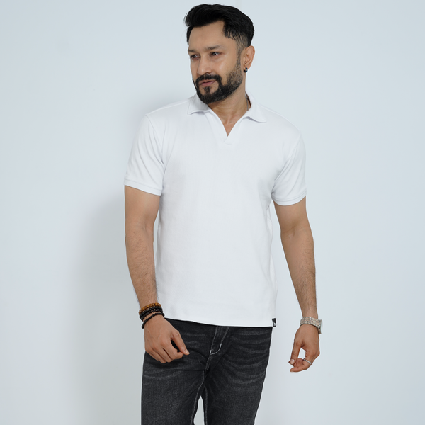 Man wearing a white polo shirt and dark jeans against a light gray background