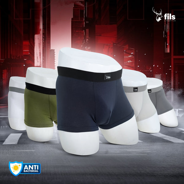 Men's underwear displayed on white cylindrical forms with a dark industrial background.